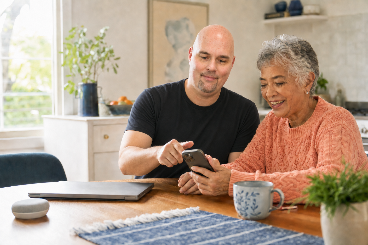 A patient technology helper showing a senior how to use her smartphone at home